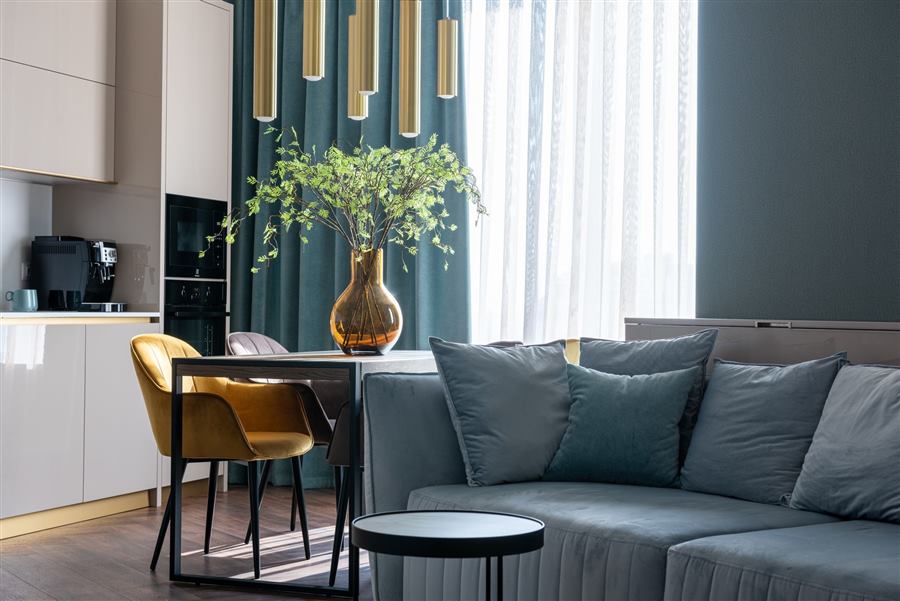 Comfortable couch with pillows and wooden table with soft chairs in modern studio apartmen