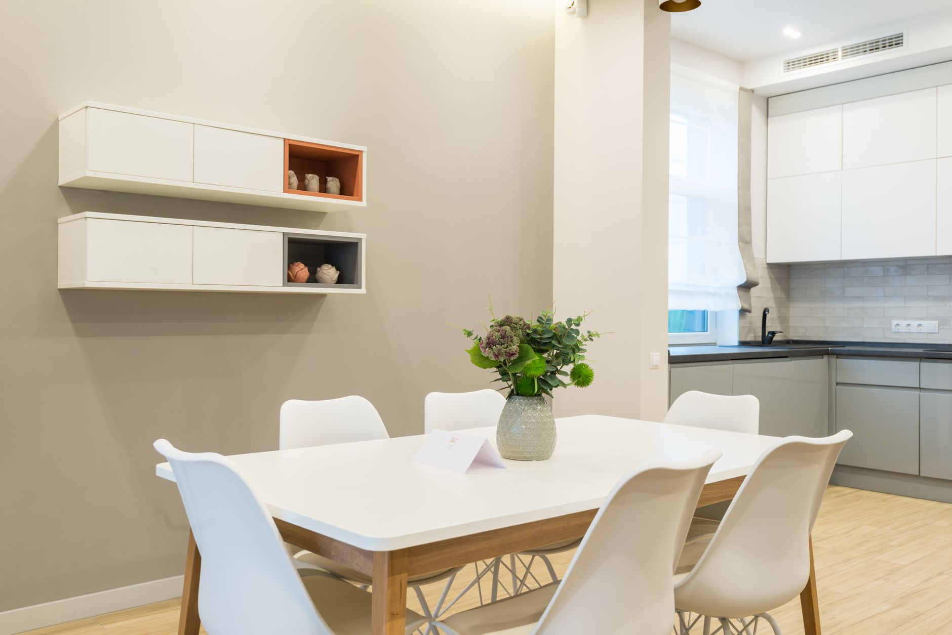 White table with green flowers and chairs placed near kitchen counter with cabinets in mod